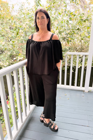 Bianca wearing the Voyager Jumpsuit in Black knit with the elasticated cape across the shoulders — Libertine The Label