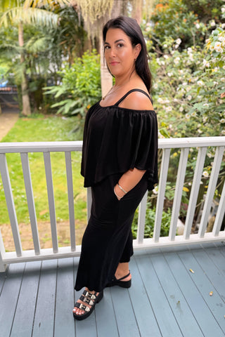 Bianca, NZ size 16 in a size L, wearing the Voyager Jumpsuit in Black knit with the cape slipped off the shoulders — Libertine The Label
