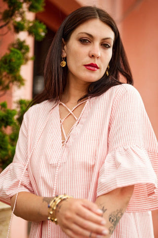 Woman wearing a pink dress with ruffled sleeves in an outdoor setting