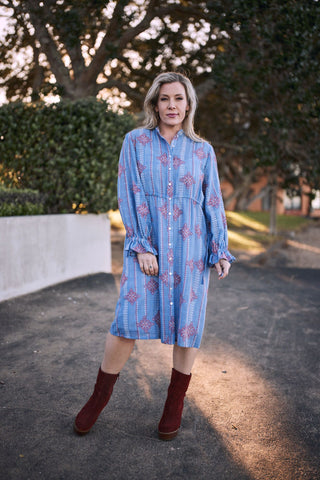 Model wearing the Oasis Heritage Stitch Dress with a buttoned front, outdoors against a tree background.