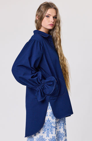 Woman wearing a blue oversized shirt with a white background