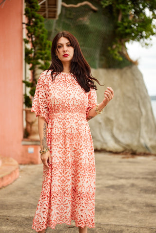 Woman wearing a coral floral dress standing outdoors with a blurred background