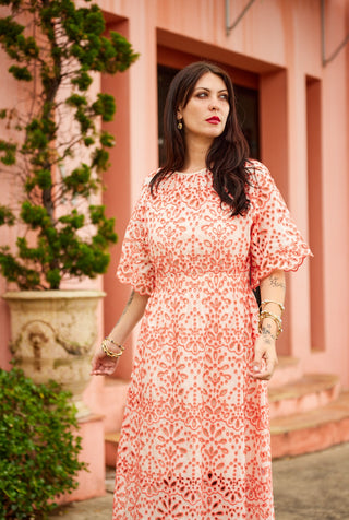 Woman in a floral dress standing in front of a pink building