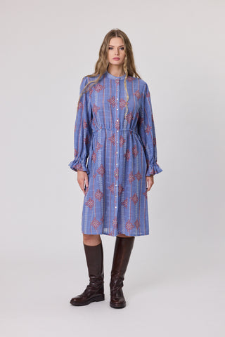 Woman wearing a blue embroidered dress with long sleeves on a white background