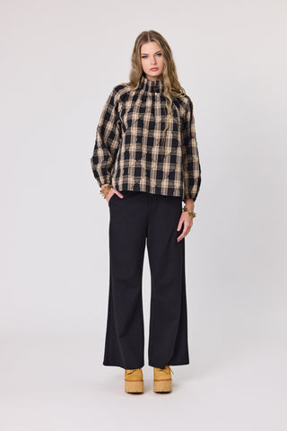 Woman wearing a plaid shirt and black pants on a white background