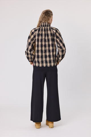 Person wearing a plaid shirt and black pants on a white background