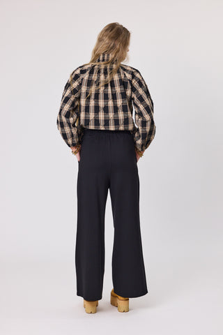 Person wearing a plaid shirt and black pants on a white background