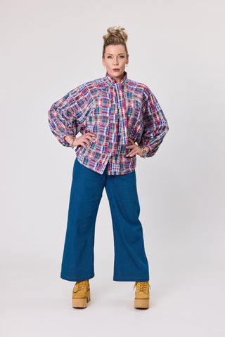Model wearing a stylish french tartan blouse with a bow and wide-leg blue pants, showcasing a trendy, bold look.