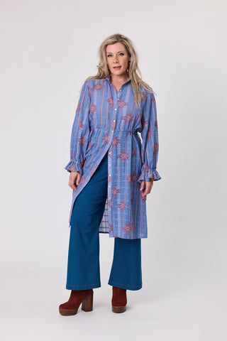 Oasis Heritage Stitch Dress modeled by a woman, featuring a blue patterned design and stylish blue pants.