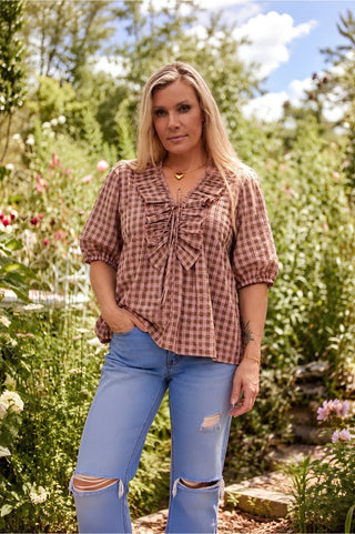 A woman outdoors wearing the marshmallow and choc latte seersucker Poet blouse, the bell sleeves and neck ties catching the breeze.