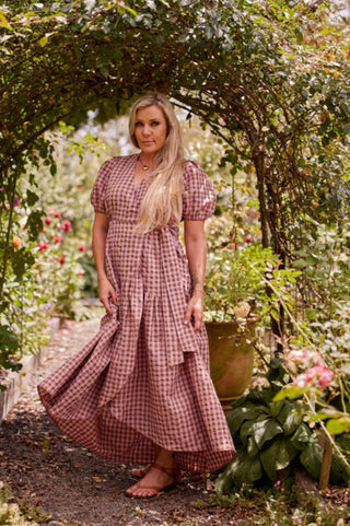 A woman in a garden wearing the marshmallow and choc latte seersucker cotton wrap maxi dress, the deep hem frill swirling around her as she turns.