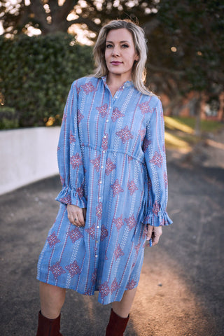 Woman wearing the Oasis Heritage Stitch Dress, featuring blue fabric with heritage stitch patterns outdoors.