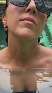 woman in pool wearing puffy stars on hoops earrings