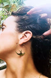 Woman wearing gold swallow hoop earrings and necklaces 