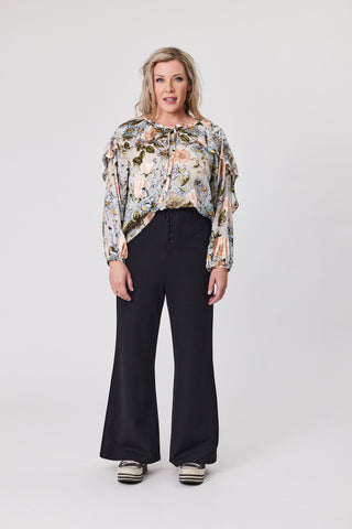 Woman wearing a floral blouse and black pants on a white background
